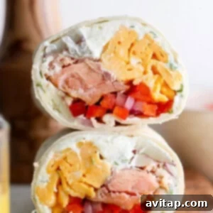 A vibrant smoked salmon breakfast burrito, filled with eggs, potatoes, and herbs, presented on a plate.