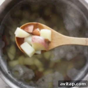 Diced red potatoes boiling in a pot of water on a stovetop.