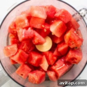 Chunks of fresh red watermelon in a food processor, ready for blending.