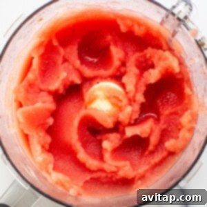 Top view of a blender filled with blended watermelon, showcasing a vivid red mixture with a swirling texture.