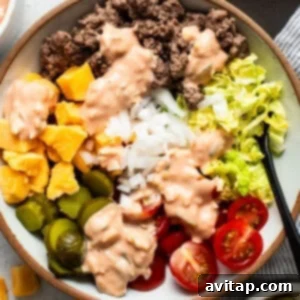 A delicious cheeseburger bowl featuring seasoned ground beef, fresh vegetables, and a creamy dressing, ready to be enjoyed.