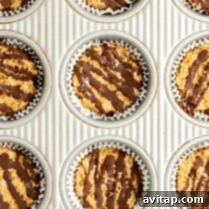 A baking sheet with nine muffin tin liners filled with a mixture topped with drizzled chocolate, showcasing the final step before chilling.