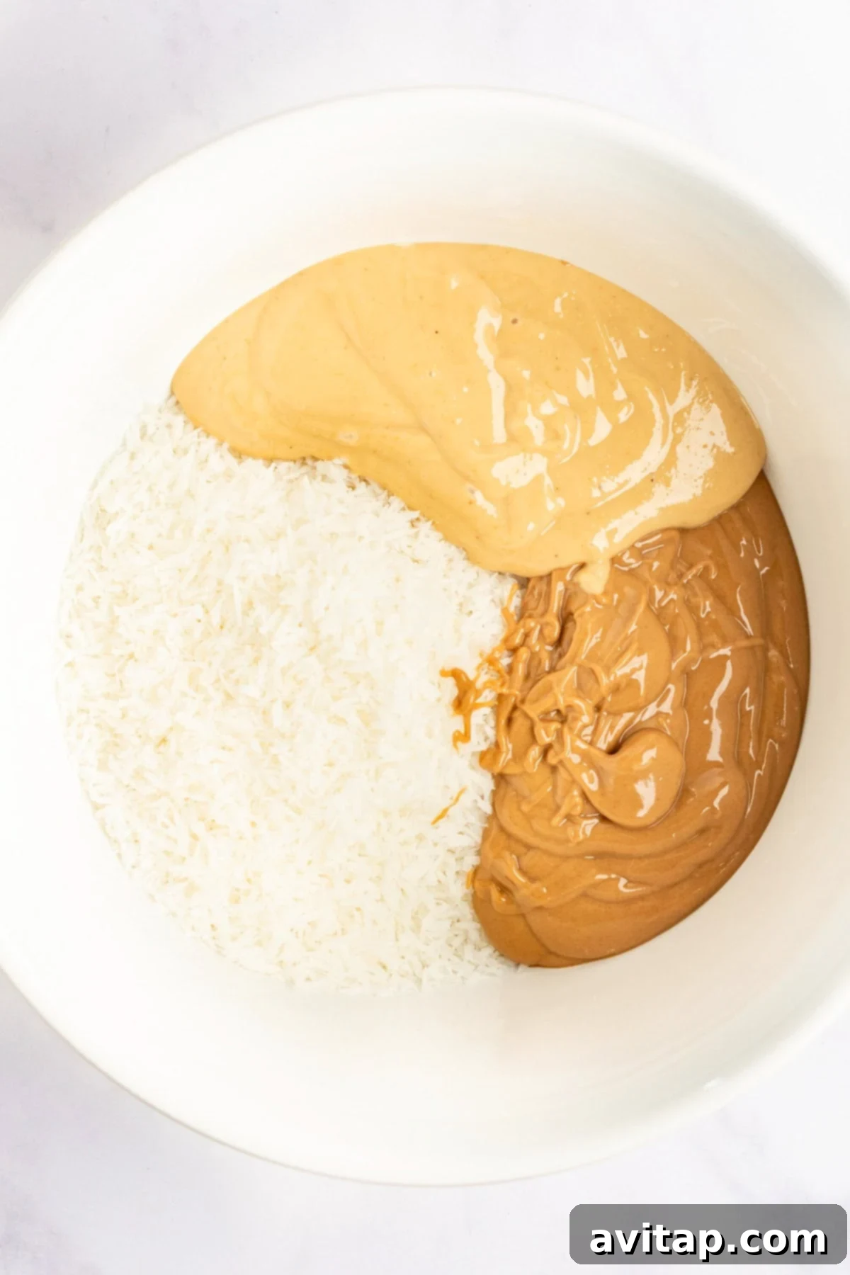 A bowl containing shredded coconut, smooth peanut butter, and crunchy peanut butter, essential for the delicious layers.
