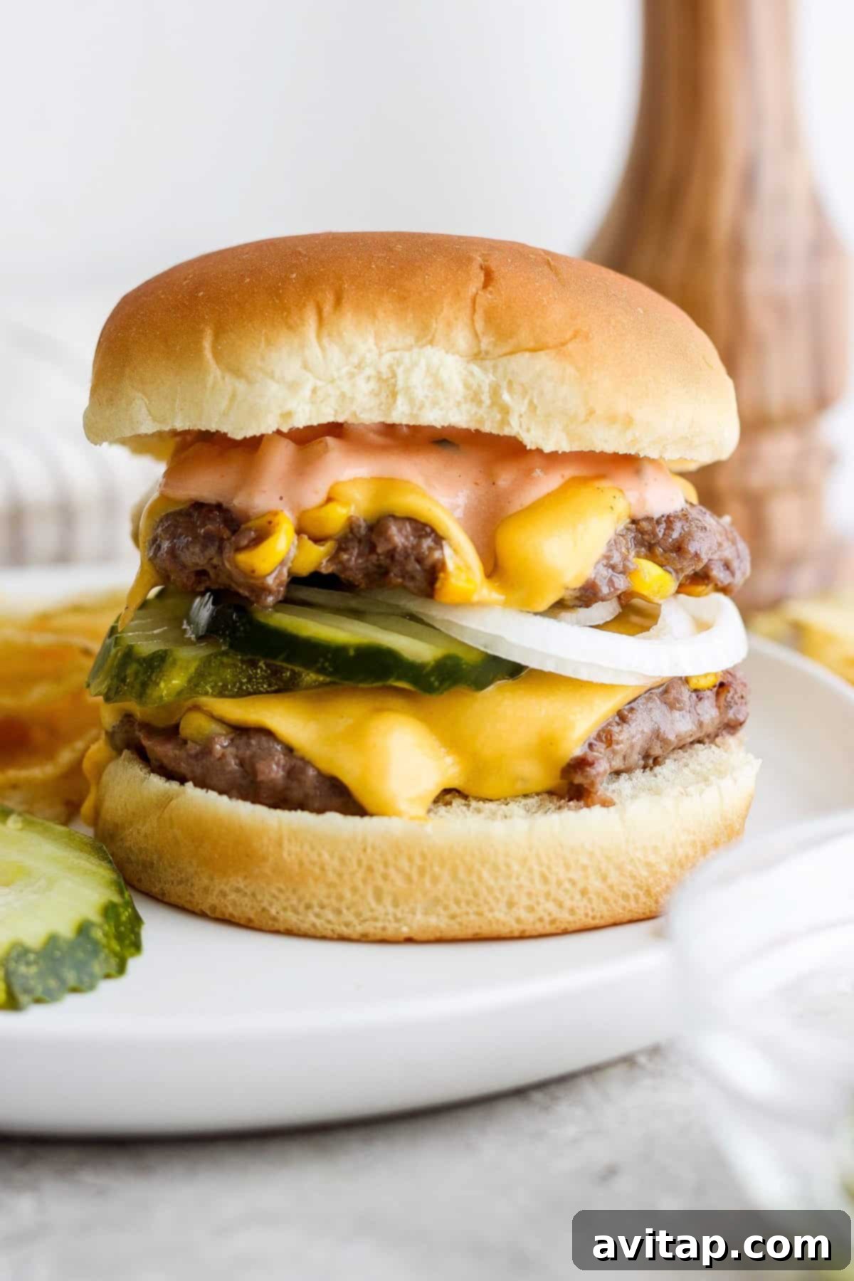 Sweet Corn Medley Smash Burger 2 Double cheeseburger with pickles on a white plate, showcasing the sweet corn relish.