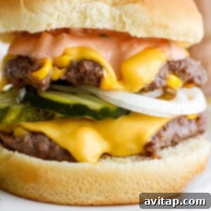 Close-up of a double cheeseburger with melted cheese, pickles, and onions, layered beautifully.