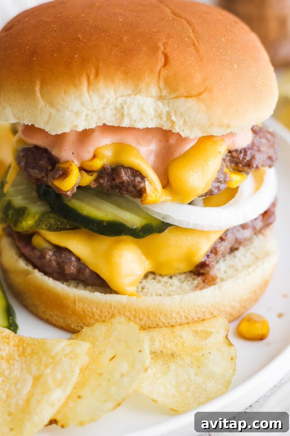 Sweet Corn Medley Smash Burger 5 Cheeseburger with lettuce, pickles, and sauce served with a side of crispy potato chips.