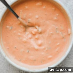 A bowl of creamy tomato soup with herbs, served with a spoon, representing the sauce.