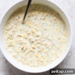 Sunshine Creamsicle Overnight Oats 9 A bowl of oat mixture with chia seeds and grated lemon zest, reminiscent of creamsicle overnight oats, stirred with a spoon.