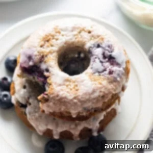 A stack of blueberry glazed donuts on a plate.