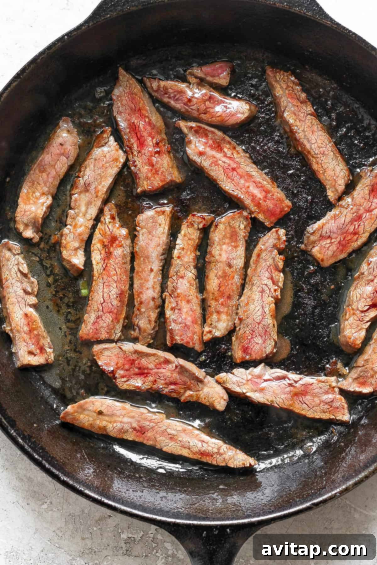 Slices of cooked meat in a black skillet.