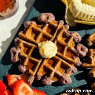Fluffy strawberry banana cottage cheese waffles topped with fresh fruit and a pat of butter, perfect for a high-protein breakfast.