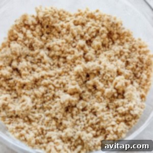 A clear glass bowl filled with a perfectly crumbly mixture, ideal for a streusel or crumble topping, resting on a light-colored countertop.