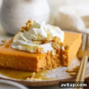 A beautifully plated slice of high-protein pumpkin bar, topped with creamy whipped cream and crunchy granola, with a small portion already enjoyed, indicating its deliciousness.