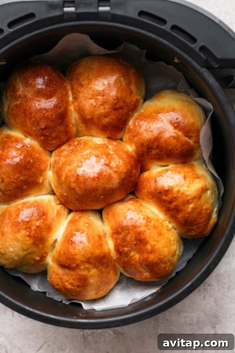 Golden brown rolls arranged in a circular shape inside an air fryer basket, lined with parchment paper, ready to be served.