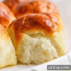 Close-up of freshly baked, golden-brown dinner rolls with a soft, fluffy interior, perfect for serving.