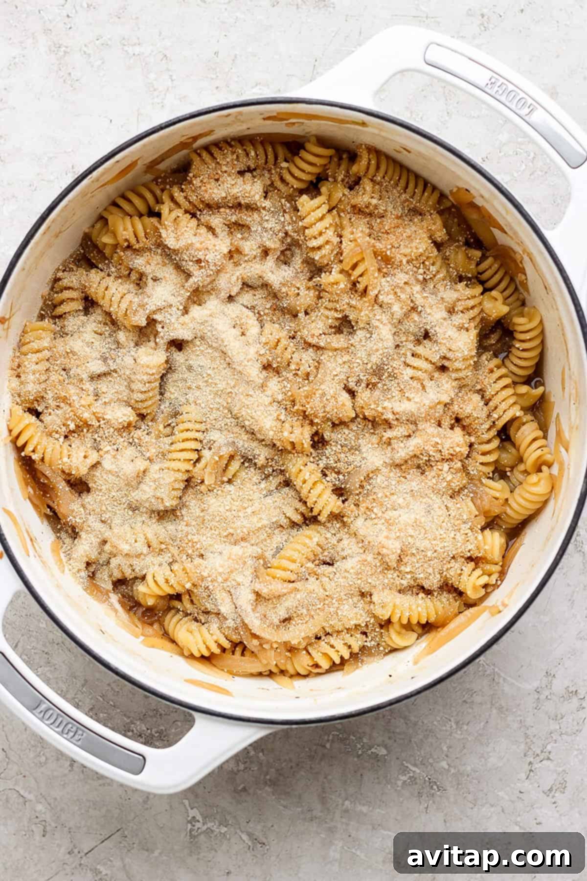 Sweet and Savory Onion Pasta 4 A pot of rotini pasta topped with a layer of grated cheese and breadcrumbs.