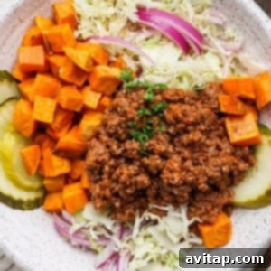 A beautifully presented Sloppy Joe Bowl featuring seasoned ground beef, vibrant diced sweet potatoes, crisp shredded cabbage, red onions, and tangy pickle slices.