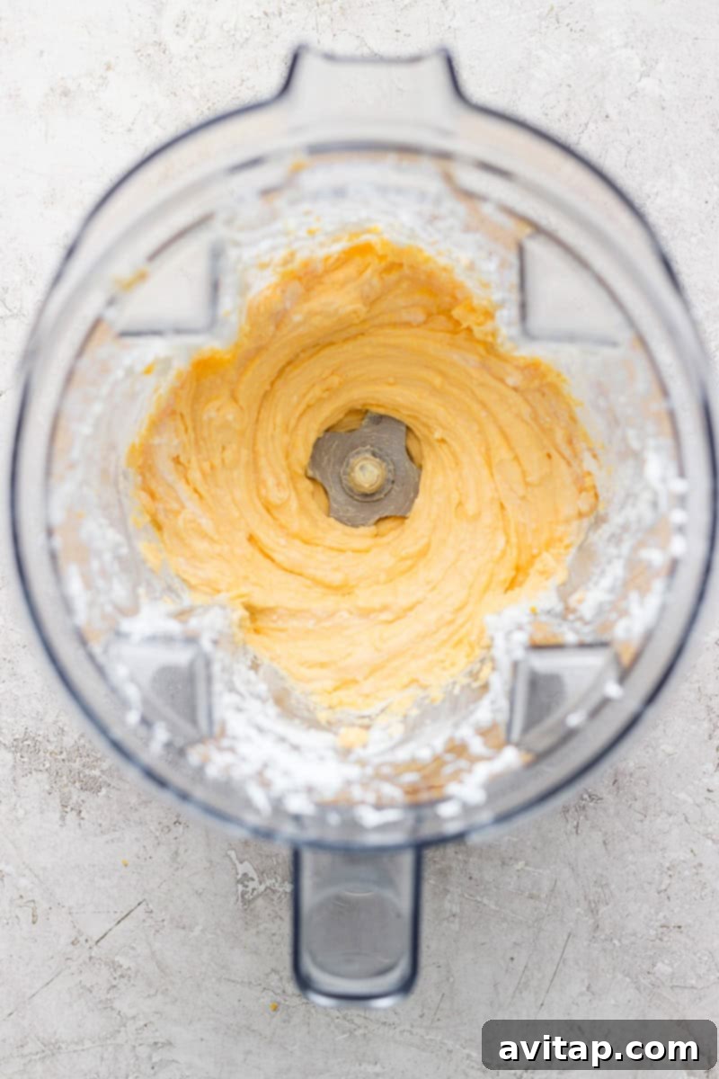 Top view of a blender with a rich, creamy, whipped mixture inside, the container's edges showing a slight dusting of white powder from the ingredients.