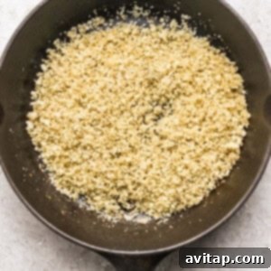 Crumbled cauliflower in a dark skillet on a light surface.