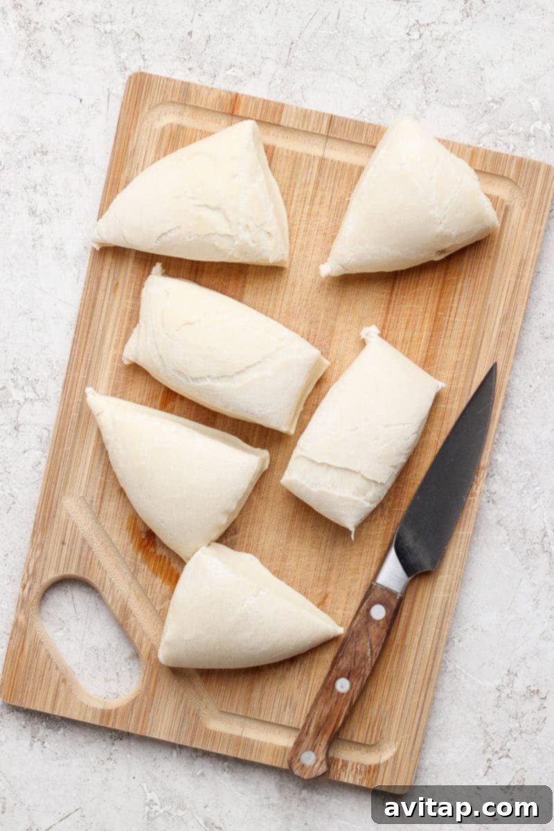 Nonna Marie's Crispy Fried Pizza 4 Sliced triangles of dough are arranged on a wooden cutting board with a knife.