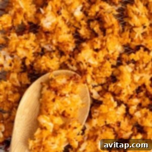 Close-up of crispy, golden-brown fried rice scattered on a wire rack with a wooden spoon.