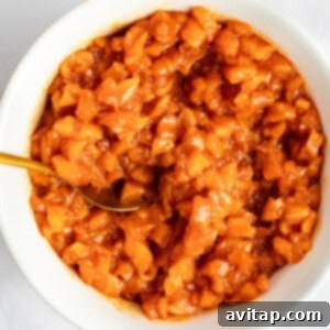 A bowl of chopped peach chutney with a golden spoon on a light surface.