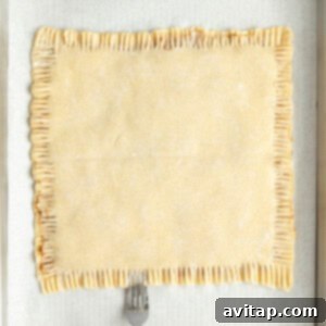 Fit Frosted Pastries 12 A fork is pressing down the edges of a rectangular pastry on parchment paper in a baking tray, sealing the filling inside.
