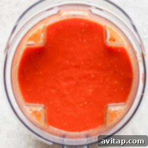 Top view of a blender containing smooth red tomato sauce on a light surface, reminiscent of the perfect partner to grilled cheese.