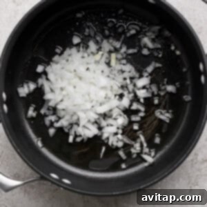 Zesty Wonton Delight 5 Chopped onions in a black pot on a gray surface.