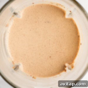 A top view of a blender containing a smooth, light brown liquid mixture.