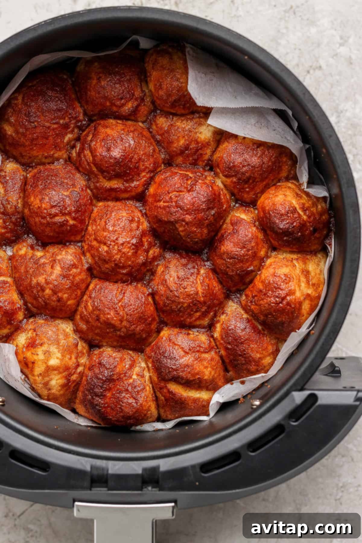 Golden brown bread rolls packed tightly in a round container with parchment paper.