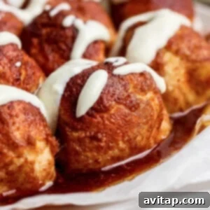 Close-up of cinnamon rolls topped with white icing and glazed with syrup.