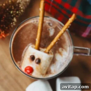 Frozen whipped cream snowman bomb with a marshmallow head decorated with chocolate chip eyes and a pretzel stick arm, ready to be dropped into hot chocolate.