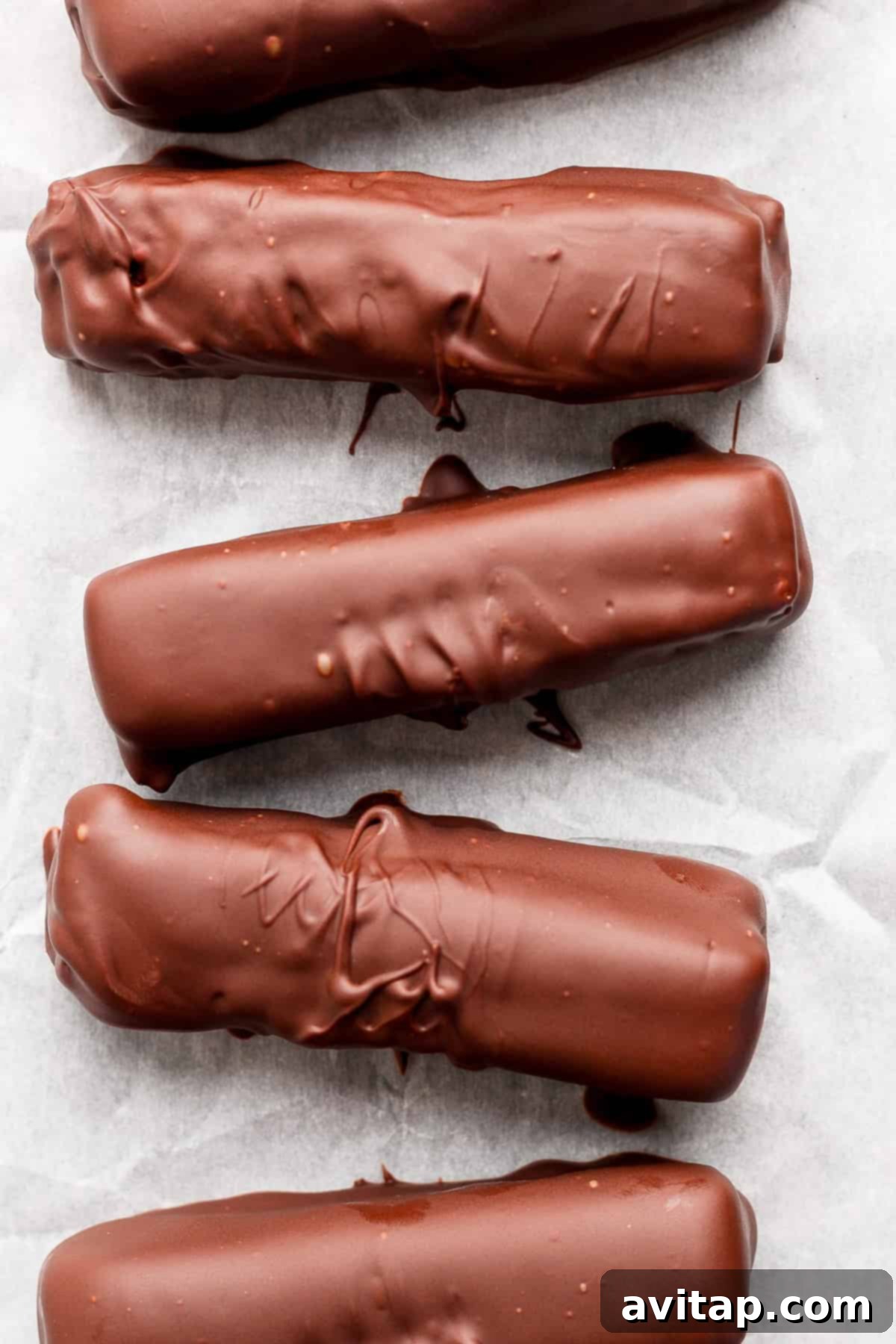 Five chocolate-coated bars arranged in a row on parchment paper.