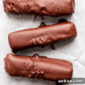 Five chocolate-coated bars arranged in a row on parchment paper.