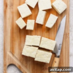 Cubed tofu on a wooden cutting board with a knife.