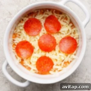 A round white dish containing shredded cheese and six slices of pepperoni neatly arranged on top, ready to be baked on a textured surface.