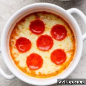 A baked dish topped with perfectly melted, bubbly cheese and six evenly spaced pepperoni slices in a white ramekin, resting on a textured surface after being removed from the oven.