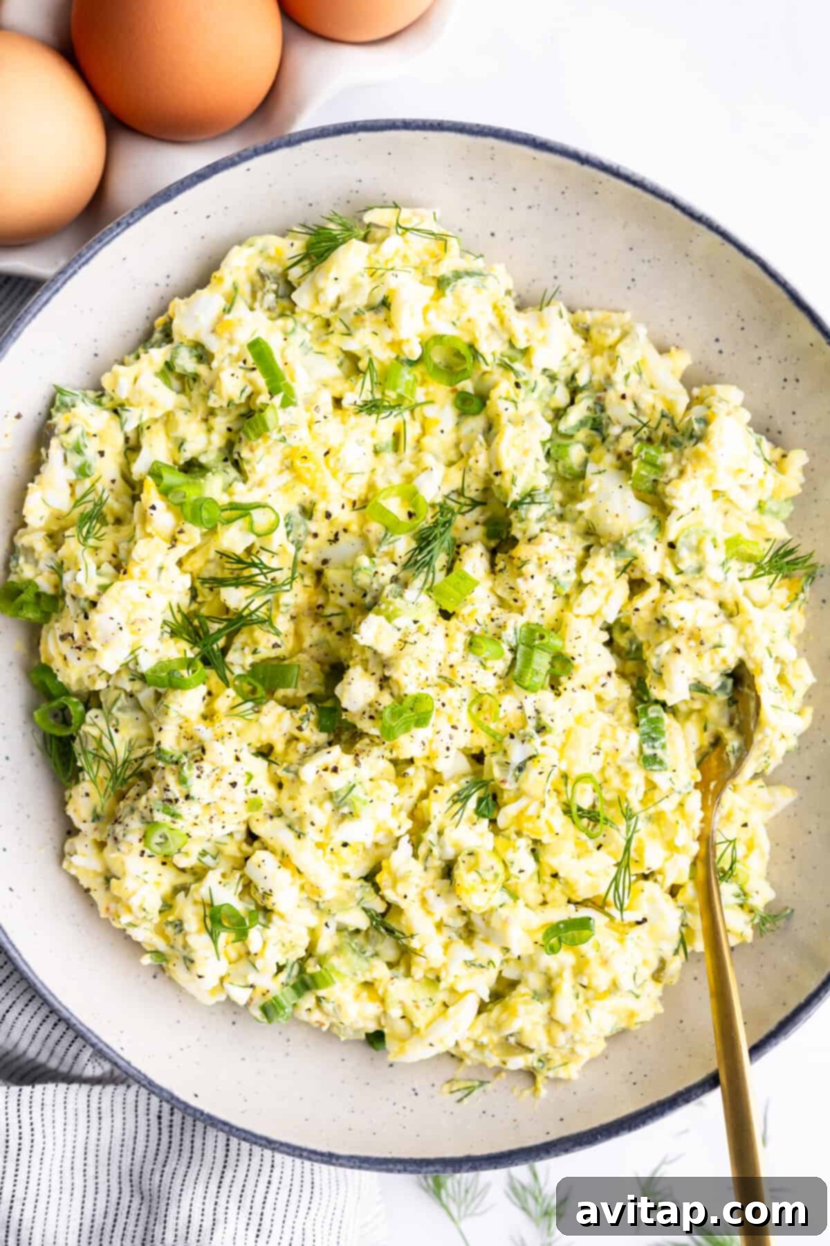 Protein-Packed Cottage Cheese Egg Salad 2 A vibrant bowl of cottage cheese egg salad, garnished with fresh chopped green onions and fragrant dill, seasoned with a sprinkle of black pepper. Three perfectly boiled eggs are artfully arranged in the background, hinting at the key ingredient.