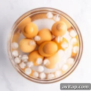 A bowl of brown eggs is submerged in icy water, resting on a clean white surface.