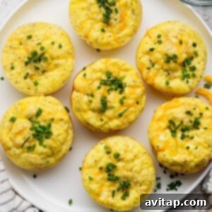 Seven egg muffins topped with chopped chives on a white plate.