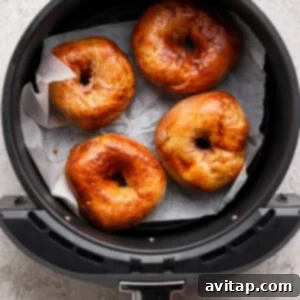 Creamy Strawberry Cottage Bagels 11 Four golden brown bagels on parchment paper inside an air fryer basket.