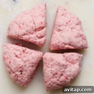 Creamy Strawberry Cottage Bagels 9 Four pieces of pinkish dough are arranged on a white, lightly floured surface.