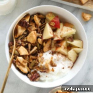 Homemade granola in a bowl with Greek yogurt and apple slices.