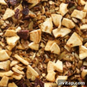 Baked apple cinnamon granola with dried fruit added, cooling on a baking sheet.