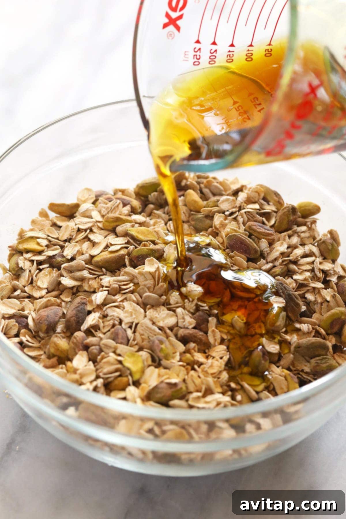 Artisan Pistachio Cherry Granola 4 Pouring maple syrup over the granola ingredients.