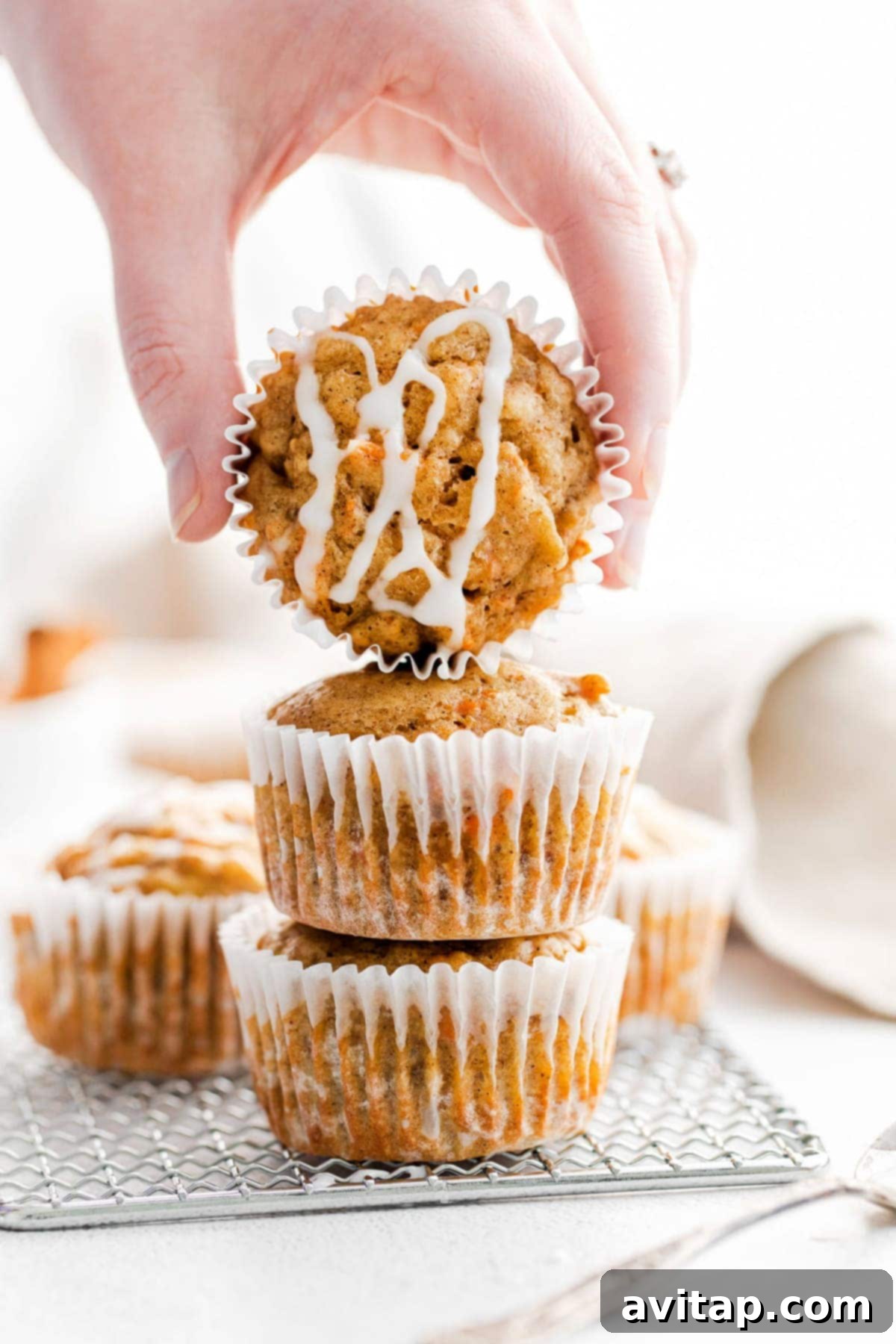 Delicious healthy carrot cake muffins with a light glaze, stacked on a cooling rack.