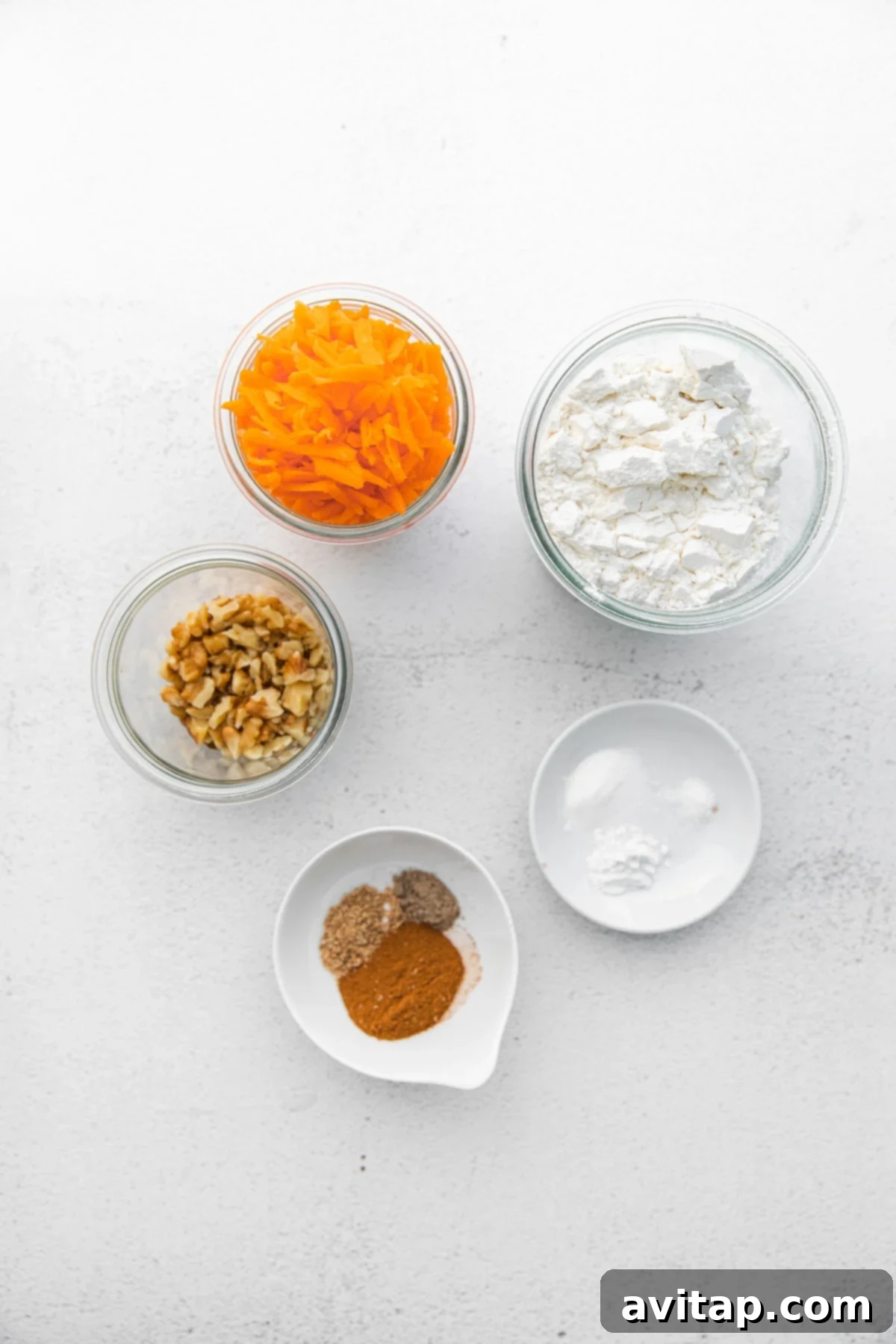 A selection of fresh, wholesome ingredients laid out for making carrot cake muffins, including carrots, flour, eggs, and spices.