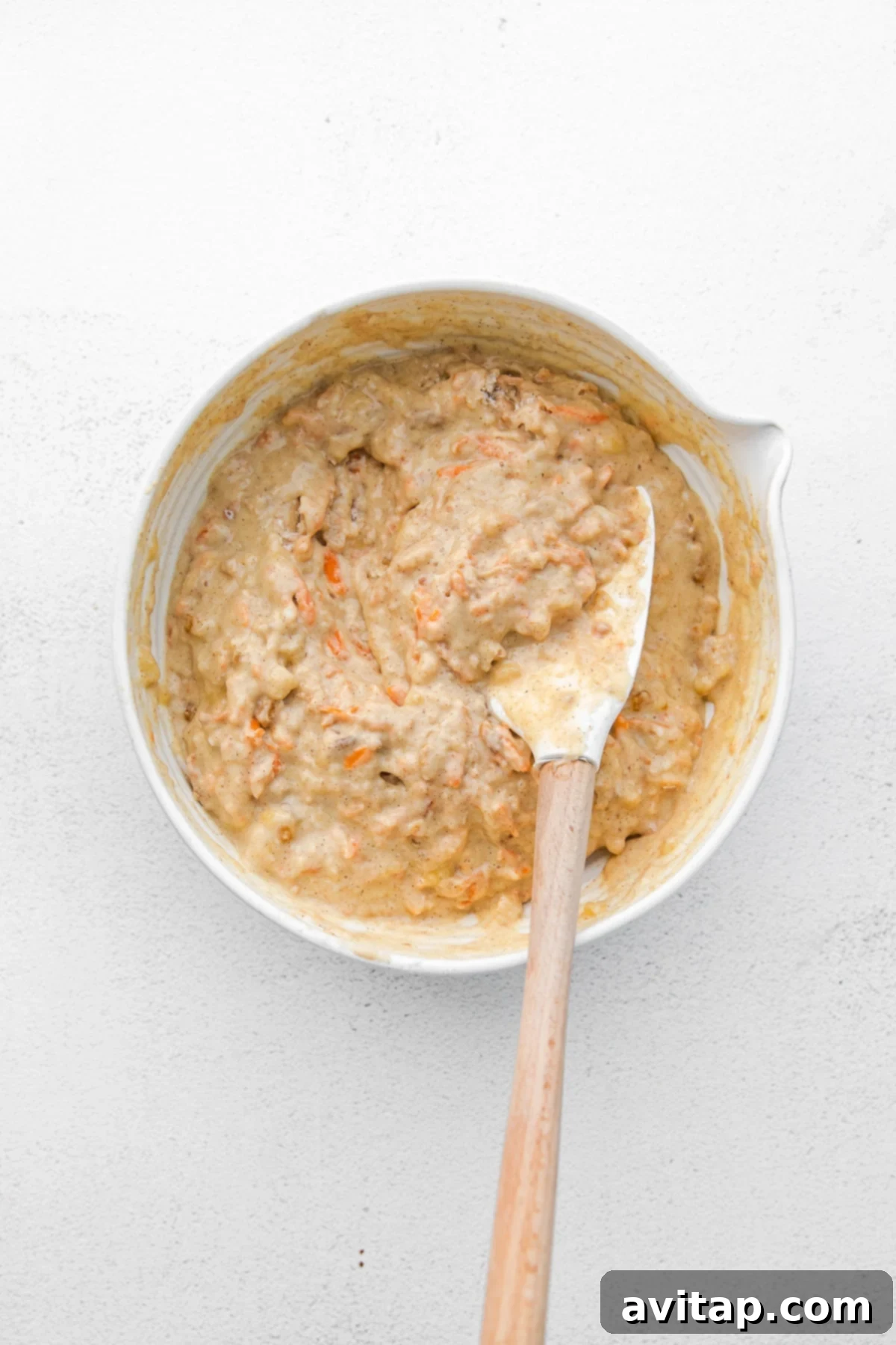 Carrot muffin batter, thick and rich with grated carrots, in a large mixing bowl, ready for baking.
