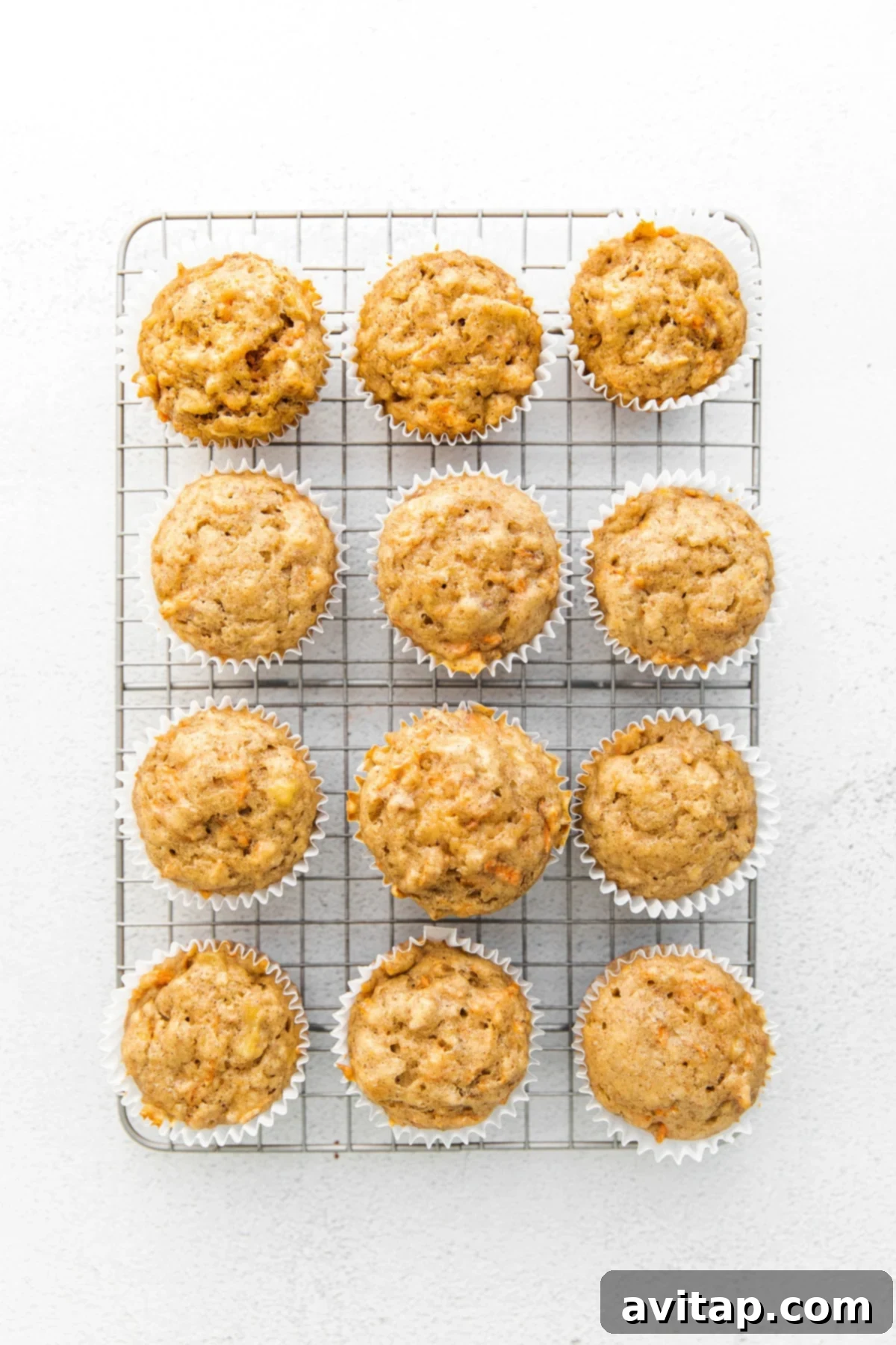 Freshly baked carrot cake muffins cooling on a wire rack, ready for glazing.